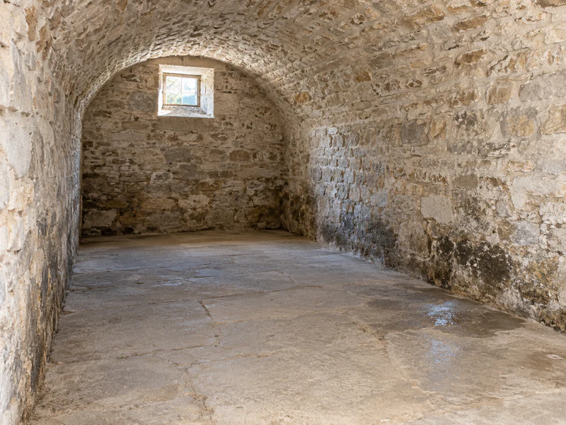 Cave voûtée en pierre, parois humides sur toute la hauteur