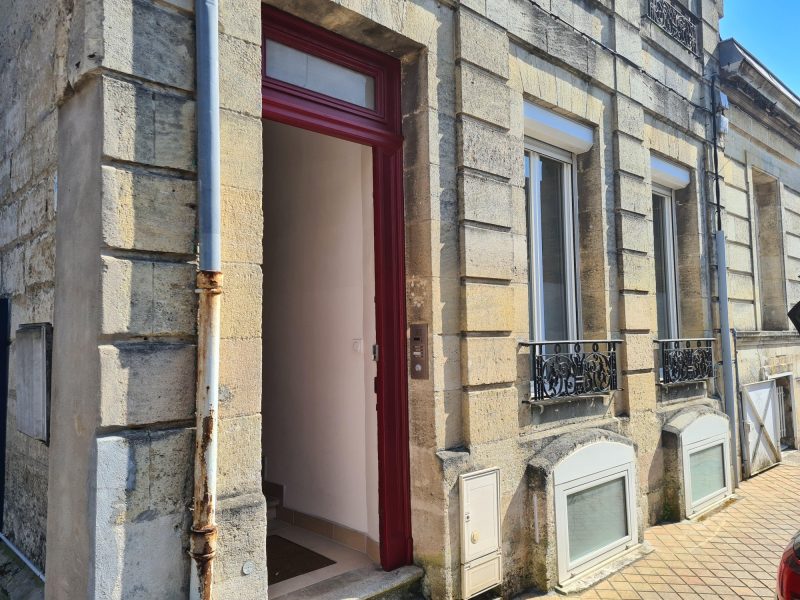 Façade d'un immeuble en pierre historique à Bordeaux présentant des traces d'humidité ascendante et une dégradation du calcin en pied de mur - intervention Mur-Tronic